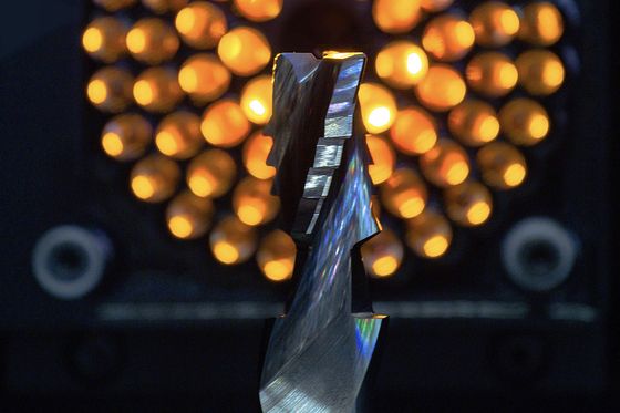 Spiralig geschliffener Fräser im Voreinstellgerät, hinterleuchtet von einem Ring orangefarbener Lichtpunkte.
